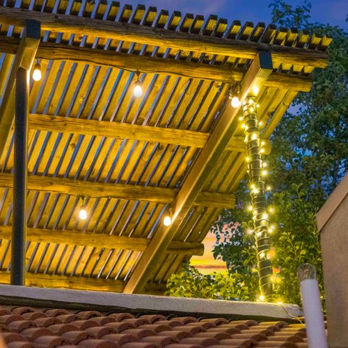 Unwind under this cozy wood pergola, lit with warm string lights—perfect for evening chats or a quiet sunset moment.