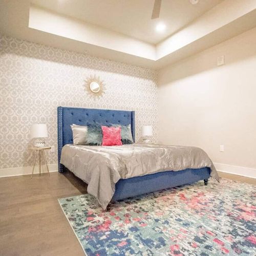 Cozy bedroom w/ a blue upholstered bed & soft, inviting linens.