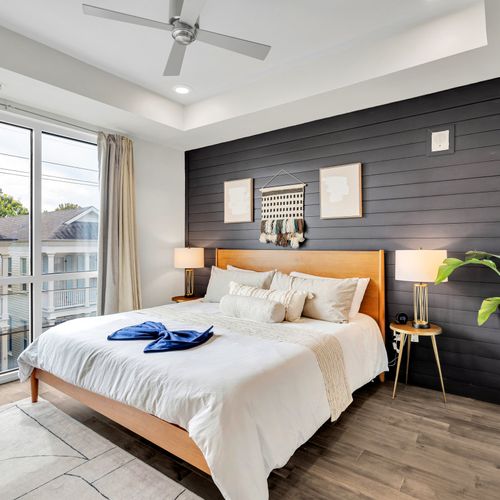 Relax in this serene bedroom featuring a sleek purple accent wall and cozy decor.