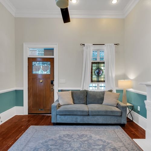 Bright living room w/ a sofa, teal walls & a welcoming, cozy vibe.