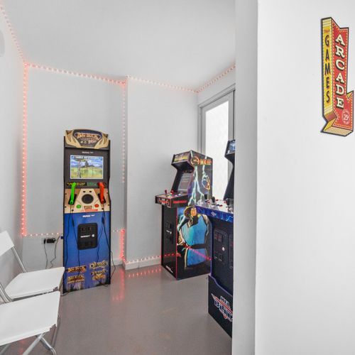 Unleash your inner gamer in this bright, inviting space adorned with iconic arcade machines and illuminated by enchanting LED lights.