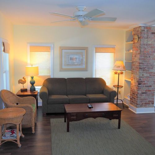 Living room: the apartment has a cozy living room with a sofa, chair, ceiling fan, and live streaming television.