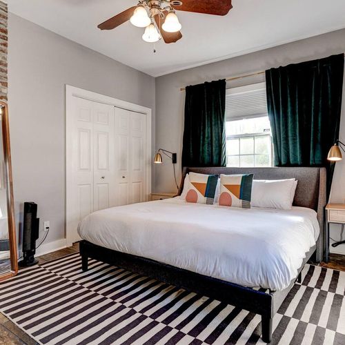 Serene master bedroom w/ crisp white bedding & vibrant teal curtains.