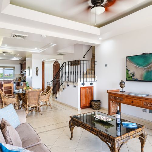 Living area with a comfortable couch, dining table, and kitchen. With stairs to the upper floor that can be rented in conjunction.