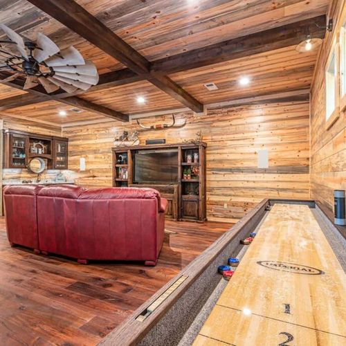 A shuffle board table as well as a flat screen TV in the game room.