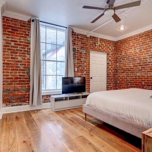 Sun-lit bedroom corner w/ exposed brick & a peaceful, airy feel.