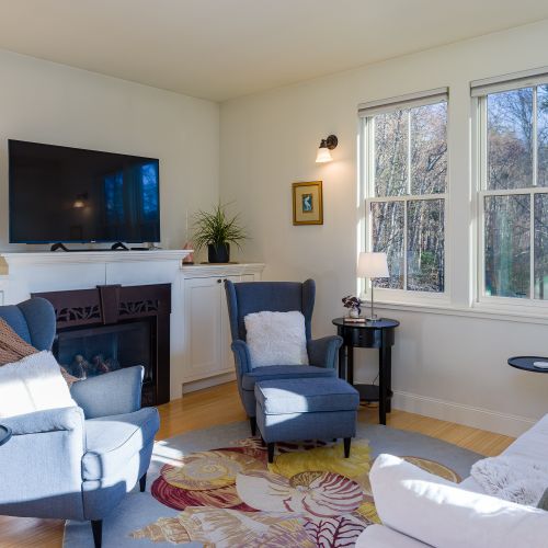 Elegant living room with fireplace, plush seating, and peaceful forest views.