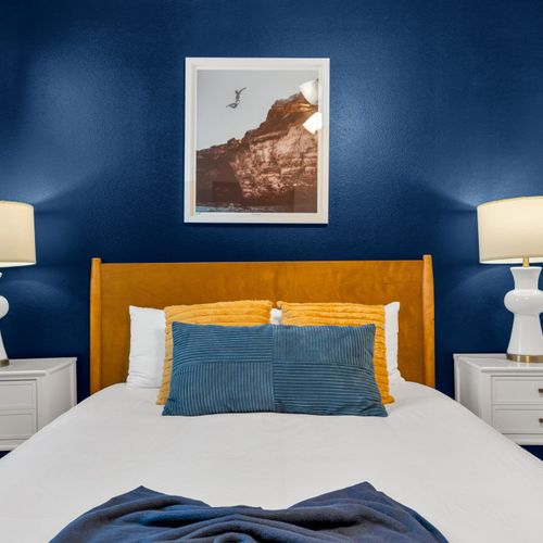 Bold navy & gold bedroom w/ a plush bed & rich accent wall.