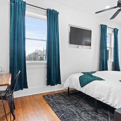 Bright bedroom 2 w/ teal curtains, a cozy bed & direct access to the balcony.