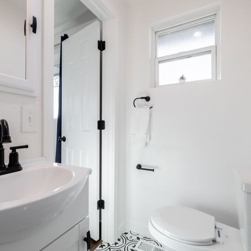The remodeled en suite bathroom features a walk in shower, single vanity and eclectic floor tiles throughout.