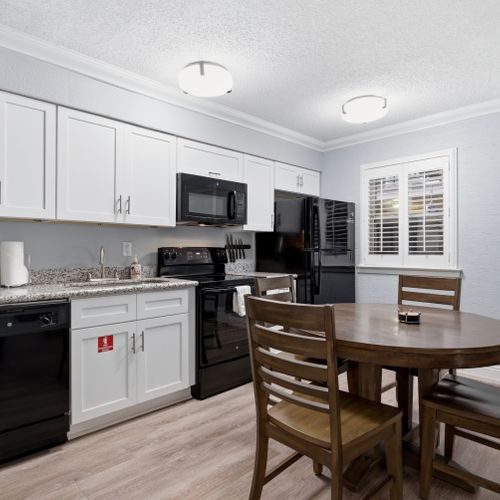 Compact kitchen w/ black appliances & white cabinetry — everything you need.