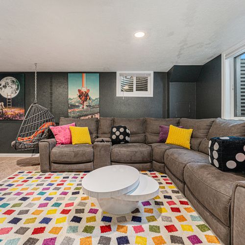 Welcome to the ultimate basement hangout! This vibrant space features a cozy sectional, colorful decor, and playful art to go with the fun games.