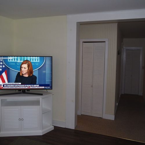 Living room: the apartment has a cozy living room with a sofa, chair, ceiling fan, and live streaming television.