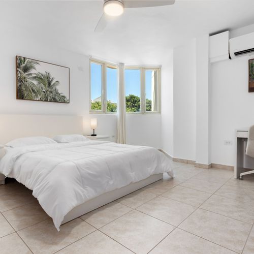 Spacious, sunlit bedroom with comfy bed, AC, and dedicated workspace.