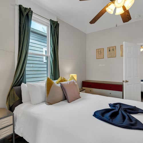 Cozy bed dressed in soft layers w/ thoughtful accent pillows & warm lighting nearby.