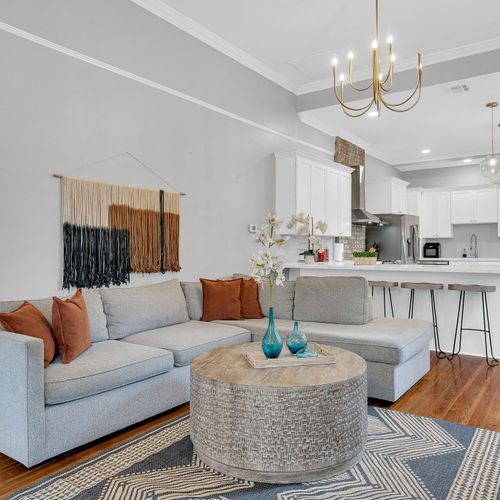 Spacious and stylish living area featuring a cozy sectional, exposed brick fireplace, and modern decor—a perfect spot to relax after exploring New Orleans.