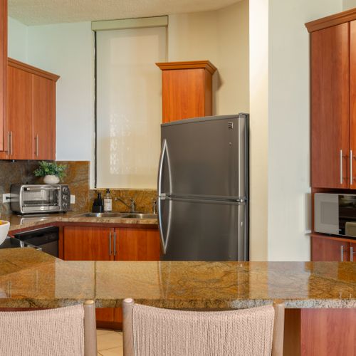 Enjoy the convenience of home cooking! This modern kitchen features granite countertops, a dishwasher, and a toaster oven.