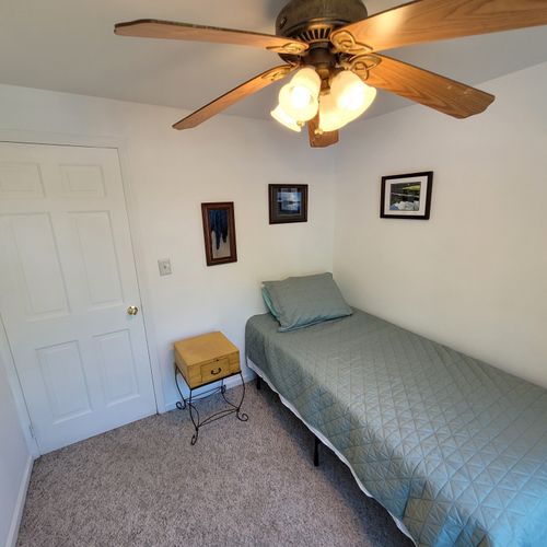 Bedroom #3 (second floor):  features a twin bed, ceiling fan, and a pedestal fan.