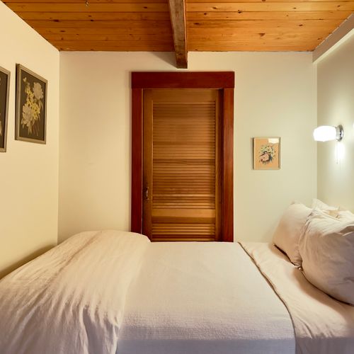 Cozy, main-floor bedroom has a queen-size bed, dresser, mirror, and luggage stand