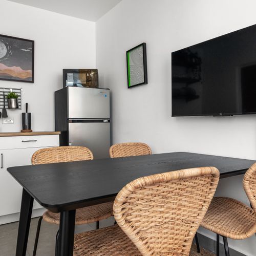 Cook, dine, and unwind in this spacious kitchen area, featuring modern appliances, a cozy dining table, and a flat-screen TV for your enjoyment.