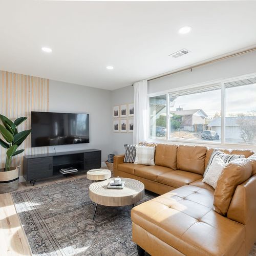 - lounge in a sun filled living space featuring a leather sectional and modern media setup
- natural wood tones, cozy textiles, and a patterned rug bring warmth and balance
- floor-to-ceiling windows and minimalist decor create an airy, relaxed vibe
