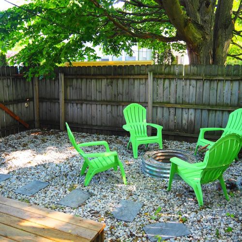 Exterior:  the fully fenced-in backyard with newly expanded deck, new hot tub, bonfire ring, propane grill, and picnic table with umbrella.