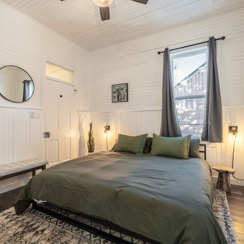 The king sized bedroom - emmeline's chambers features ship lap walls, a large window, and cozy accents.