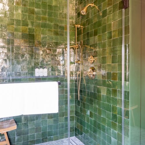 Vibrant tile accentuates a magnificent shower with brass fixtures.