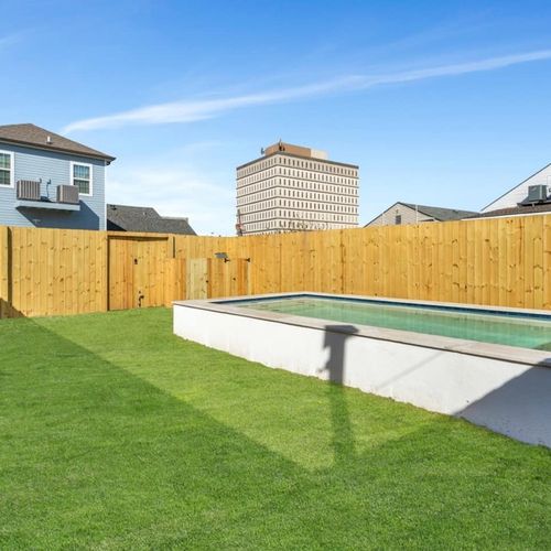 Fully-fenced pool w/ lush green lawn surrounding it — plenty of space to relax outside.