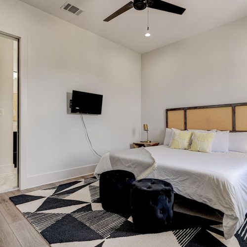 Bedroom w/ a woven headboard, pocket door & clean, airy finishes.