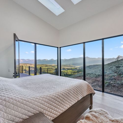 Serene bedroom offering luxurious bedding, mountain views, restful environment.