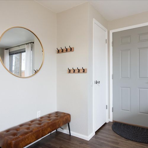 The stylish and inviting entryway with mid-mod bench, brass mirror and industrial hooks greet you upon arrival.