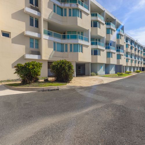 Stunning modern condominium building with beautiful architecture and lush landscaping.