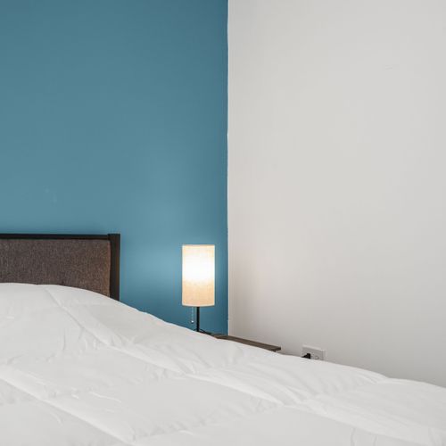 Unwind in a stylish, modern room with a cozy queen bed set against a vibrant blue accent wall.