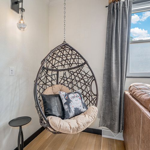 In the living space, a swinging wicker chair adds a touch of whimsy and relaxation, inviting you to unwind in comfort while enjoying the surroundings.