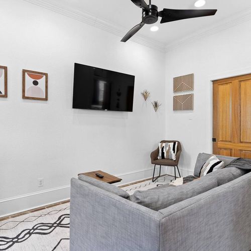 Clean, bright living area w/ wall-mounted TV — laid-back comfort awaits.