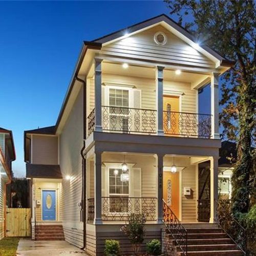 Classic New Orleans-style home w/ a charming front porch & bold orange door.