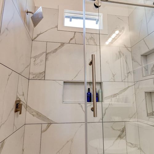 Stunning marble-look tiled shower w/ a built-in niche — a luxurious rinse awaits.