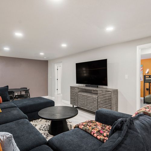 The spacious downstairs living area features ample seating and a large tv, creating the perfect spot for relaxation and entertainment with family and friends.