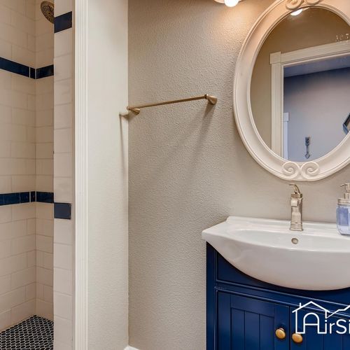 - walk in shower features crisp white tile with bold navy trim for a classic touch
- elegant navy vanity with gold handles and round mirror adds vintage charm
- wall mounted lighting and neutral walls create a spa like bathroom vibe