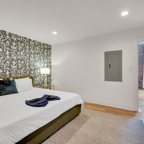 Sink into soft, stylish comfort in the cozy bedroom featuring a king-size bed, warm lighting, and calming tones—your personal retreat after exploring the city