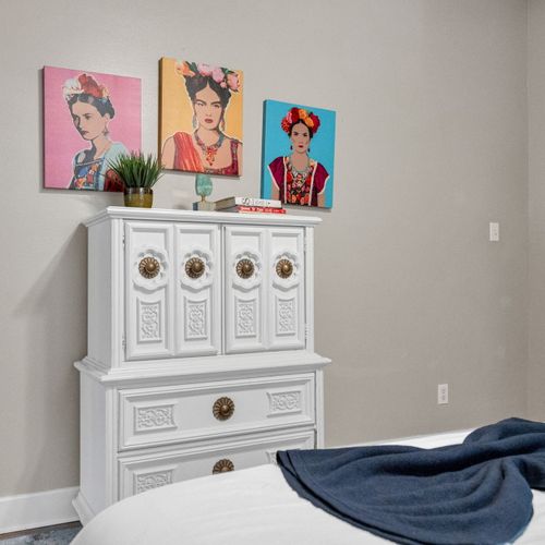 Dresser w/ curated décor & vibrant wall art adding personality to the space.