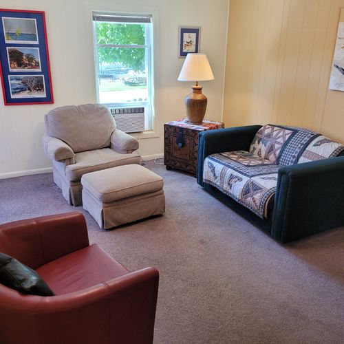 Living room:  features a loveseat, comfy chairs, live-streaming television with roku, and a ceiling fan.