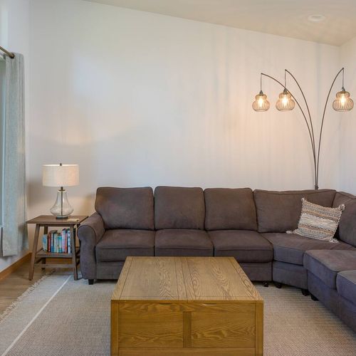 Wooden barn-sliding doors open to a media room with a large sectional sleeper sofa and TV. The couch converts to a queen-sized bed, perfect for larger groups.