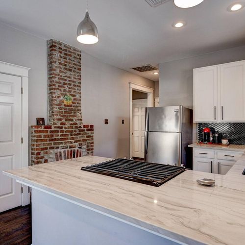 Bright kitchen w/ exposed brick accent & stainless steel fridge.