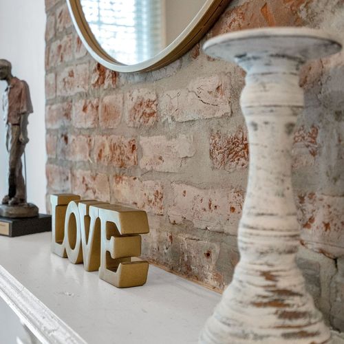 Elegant touch of 'LOVE' — this cozy mantel features soft florals and rustic exposed brick, reflecting the heart of New Orleans' charm.