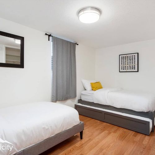 - comfortable twin beds with a pull out trundle offer flexible sleeping options
- black framed mirror and modern prints add a sharp, minimalist touch
- ideal for kids or friends, with warm wood floors and a soft lit glow