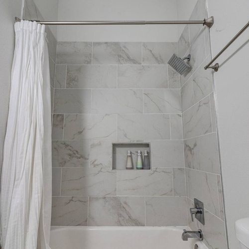 Tiled shower w/ sleek marble-look walls — a refreshing way to start or end your day.