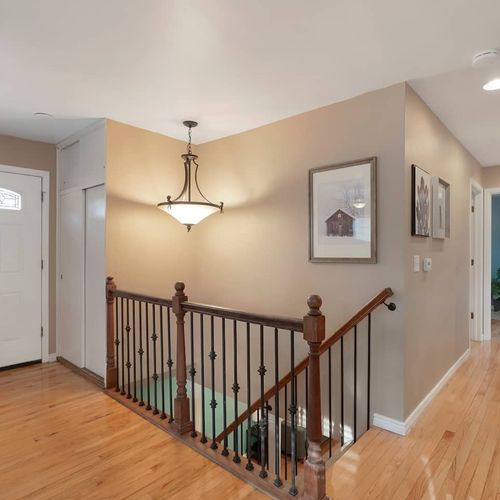 - bright entryway with warm wood floors, elegant chandelier, and stair access
- framed artwork and soft lighting create a welcoming first impression
- stairs lead directly to lower level living areas, adding easy flow throughout
