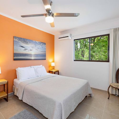 The bedroom has oen queen size bed and a view of the back yard.